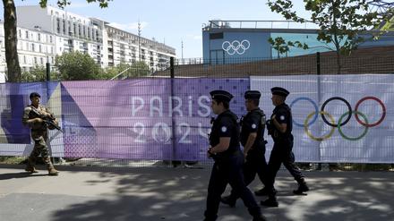 Ein Soldat und Polizisten patrouillieren neun Tage vor Beginn der Olympischen Spiele vor olympischen Bannern von Paris 2024.