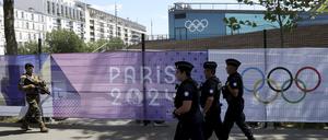 Ein Soldat und Polizisten patrouillieren neun Tage vor Beginn der Olympischen Spiele vor olympischen Bannern von Paris 2024.