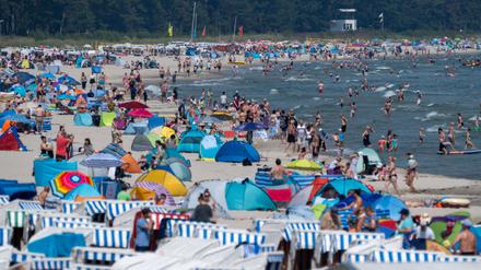Touristen spazieren und baden am Strand der Insel Rügen.