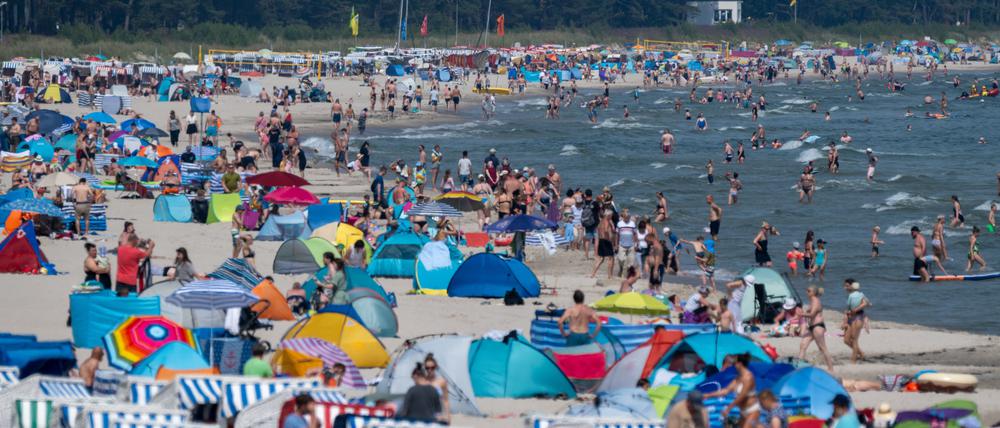 Touristen spazieren und baden am Strand der Insel Rügen.