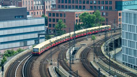 Ein S-Bahn fährt vom Hauptbahnhof kommend zwischen Gebäuden der Charité und Bürohäusern in Richtung Friedrichstraße. 