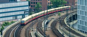 Ein S-Bahn fährt vom Hauptbahnhof kommend zwischen Gebäuden der Charité und Bürohäusern in Richtung Friedrichstraße. 