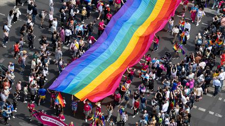 Menschen ziehen auf der 45. Berlin Pride-Parade zum Christopher Street Day (CSD) mit einer Regenbogenfahne durch die Stadt.
