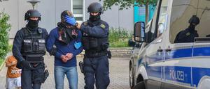 Bewaffnete Polizisten führen während einer Drogenrazzia einen Mann ab.