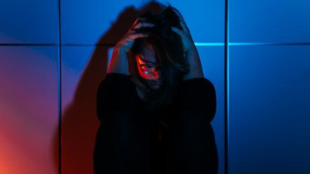 Eine beängstigte Frau sitzt gedrängt an eine Wand.