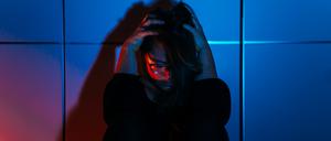 Eine beängstigte Frau sitzt gedrängt an eine Wand.