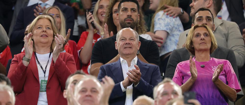 Bundeskanzler Olaf Scholz (SPD) steht zwischen seiner Frau Britta Ernst (r) und Bärbel Bas (SPD), Bundestagspräsidentin, auf der Tribüne bei EM-Spiel Deutschland gegen Dänemark.
