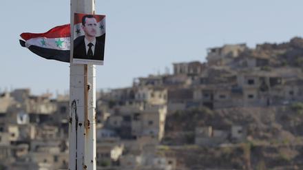 Ein Portrait von Baschar al-Assad, Präsident von Syrien, hängt an einem Pfeiler. 