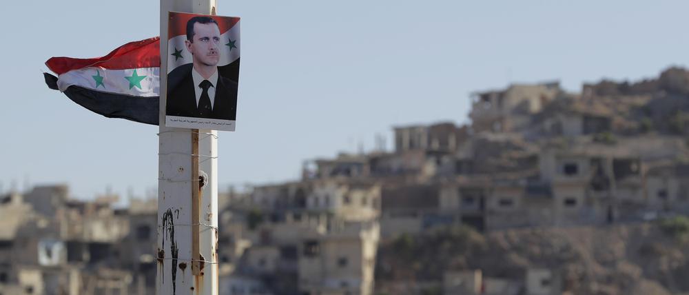 Ein Portrait von Baschar al-Assad, Präsident von Syrien, hängt an einem Pfeiler.