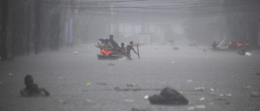 Retter paddeln am 24. Juli 2024 in einer überfluteten Straße in Manila inmitten starker Regenfälle.