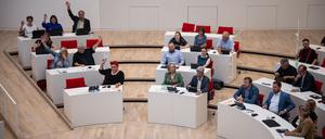 Mitglieder der Fraktion von Die Linke heben die Hände während einer Abstimmung im Landtag.