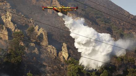 Ein Löschflugzeug wirft Wasser über einem Waldbrand auf einem Berg in Sizilien ab.