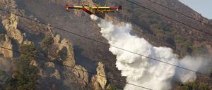 Ein Löschflugzeug wirft Wasser über einem Waldbrand auf einem Berg in Sizilien ab.