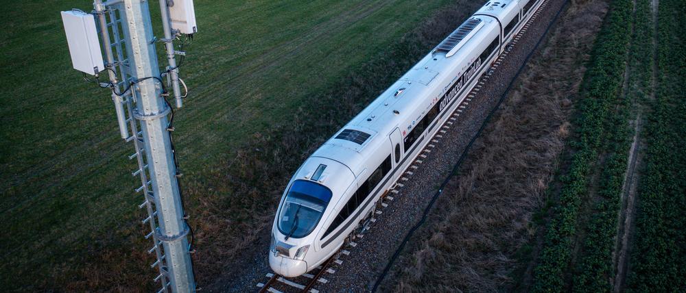 Ein Testzug der Deutschen Bahn fährt an einem Antennenmast vorbei (Luftaufnahme mit einer Drohne).
