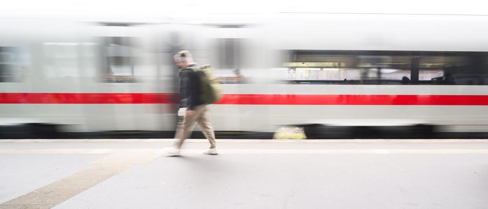 Ein ICE fährt durch den Hauptbahnhof in Hannover an einer wartenden Reisenden vorbei.