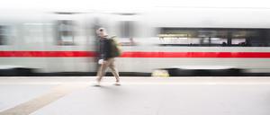Ein ICE fährt durch den Hauptbahnhof in Hannover an einer wartenden Reisenden vorbei.