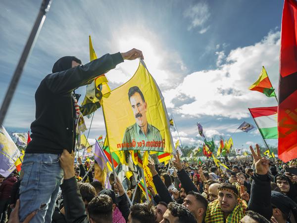 Menschen nehmen an der zentralen Feier zum kurdischen Neujahrsfest «Newroz» teil und schwenken dabei Fahnen. Ein Mann hält eine Flagge mit dem Konterfei von Abdullah Öcalan, dem Führer und Gründer der in vielen Ländern verbotenen und als Terrororganisation eingestuften kurdischen Arbeiterpartei PKK. Aus dem gesamten Bundesgebiet sind tausende Menschen im Rebstockpark zusammengekommen, um das kurdischen Neujahrsfest «Newroz» zu feiern. +++ dpa-Bildfunk +++