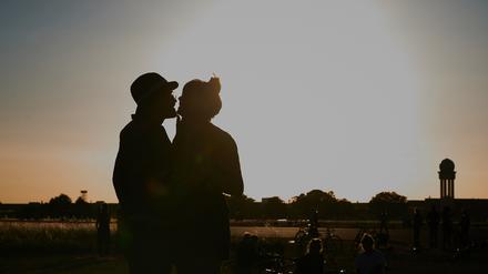 Ein Pärchen küsst sich bei Abendstimmung auf dem Tempelhofer Feld.