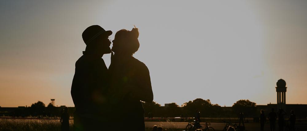 Ein Pärchen küsst sich bei Abendstimmung auf dem Tempelhofer Feld.