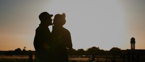 Ein Pärchen küsst sich bei Abendstimmung auf dem Tempelhofer Feld.