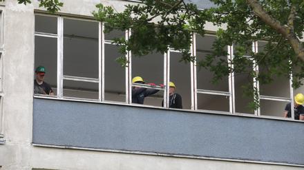 Bauarbeiter entfernen Fensterrahmen auf der Baustelle eines Gymnasiums.
