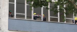 Bauarbeiter entfernen Fensterrahmen auf der Baustelle eines Gymnasiums.