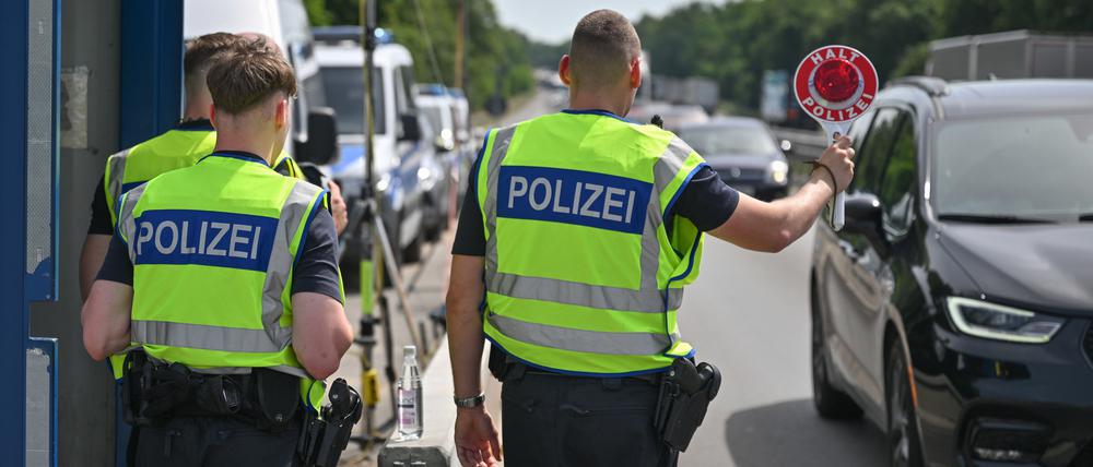 Beamte der Bundespolizei stehen auf der Autobahn A12 nahe dem deutsch-polnischen Grenzübergang und stoppen ein Auto bei der Einreise nach Deutschland.