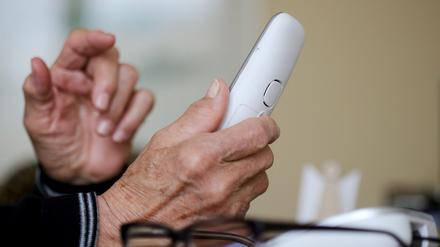 Ein Senior hält einen Telefonhörer in der Hand