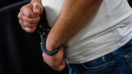 Ein Angeklagter steht mit Handschellen in einem Gerichtssaal.