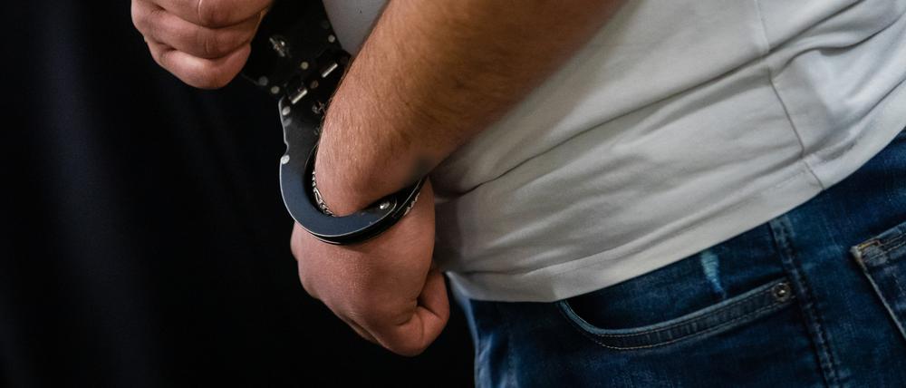 Ein Angeklagter steht mit Handschellen in einem Gerichtssaal.