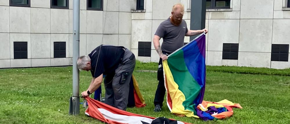 Vor dem Amtsgericht Kreuzberg holen Mitarbeiter die Berlin-Flagge ein, um die Regenbogenflagge zu hissen.
