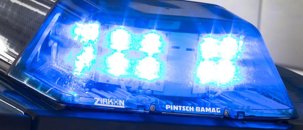 Eine Blaulicht leuchtet auf dem Dach eines Polizeiwagens. Im Hintergrund steht ein weiterer Streifenwagen.