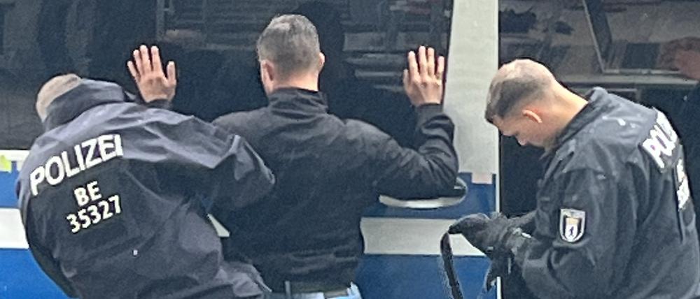 Polizisten durchsuchen einen Neonazi am Rande des CSD in Berlin.