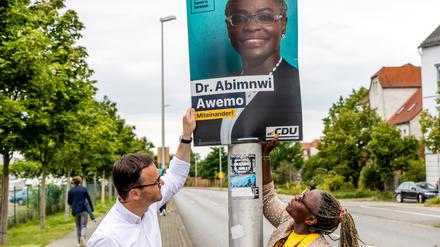 Jan Redmann, Landesvorsitzender der CDU Brandenburg, und Adeline Abimnwi Awemo, CDU-Kandidatin für den Landtag Brandenburg, hängen ein Wahlplakat für die Landtagswahl auf. 