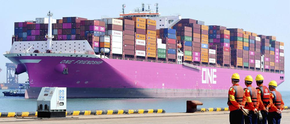 Hafenarbeiter warten in Qingdao auf die Ankunft eines Containerschiffs an einem Dock.