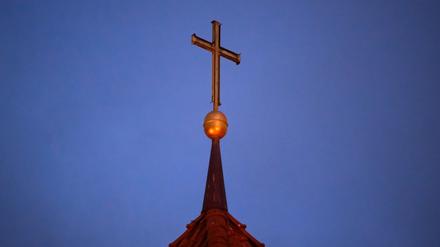 Ein Kreuz auf einer Kirchturmspitze.