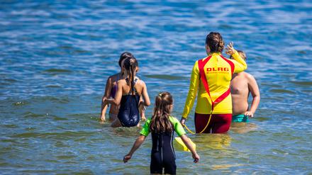 Eine Rettungsschwimmerin geht mit Kindern zum Schwimmkurs der DLRG ins Wasser.