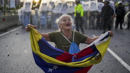 Eine Frau hält eine venezolanische Flagge vor einem Polizeikordon bei Demonstrationen gegen das offizielle Wahlergebnis in Caracas am 29. Juli 2024.