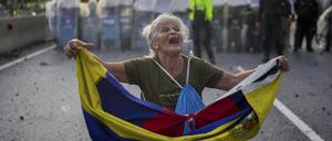 Eine Frau hält eine venezolanische Flagge vor einem Polizeikordon bei Demonstrationen gegen das offizielle Wahlergebnis in Caracas am 29. Juli 2024.