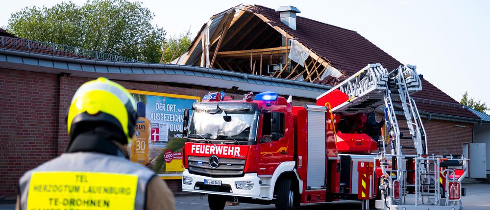 Einsatzkräfte der Feuerwehr sind bei einem eingestürzten Dach eines Supermarktes im Einsatz. 
