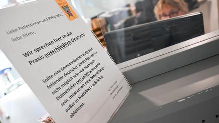 Ein Schild mit der Aufschrift „Wir sprechen hier in der Praxis ausschließlich Deutsch“ steht auf einem Tresen an dem Empfangsbereich einer Praxis für Kinder- und Jugendmedizin in Kirchheim unter Teck. 