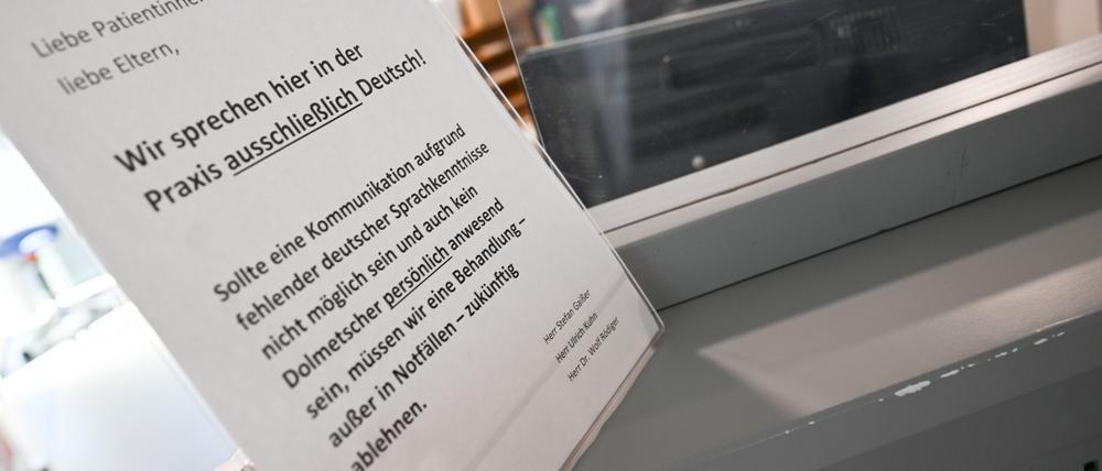 Ein Schild mit der Aufschrift „Wir sprechen hier in der Praxis ausschließlich Deutsch“ steht auf einem Tresen an dem Empfangsbereich einer Praxis für Kinder- und Jugendmedizin in Kirchheim unter Teck. 