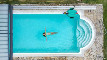 Eine Person schwimmt in einem Pool (Luftaufnahme mit einer Drohne)