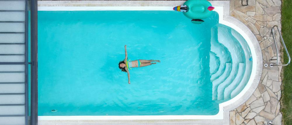 Eine Person schwimmt in einem Pool (Luftaufnahme mit einer Drohne)