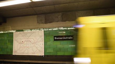 Wegfahrende U-Bahn, grün gekachelte Wand im U-Bahnhof Bismarckstraße, daneben eine U-Bahngleiskarte 