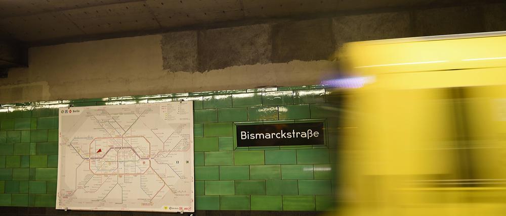 Wegfahrende U-Bahn, grün gekachelte Wand im U-Bahnhof Bismarckstraße, daneben eine U-Bahngleiskarte 