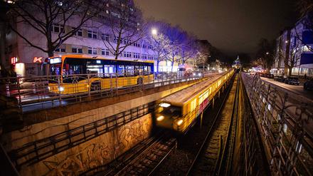 Ein Bus und eine U-Bahn der Berliner Verkehrsbetriebe fahren bei Dunkelheit am Nollendorfplatz in Berlin.