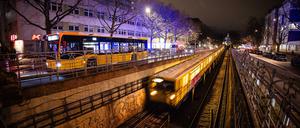 Ein Bus und eine U-Bahn der Berliner Verkehrsbetriebe fahren bei Dunkelheit am Nollendorfplatz in Berlin.