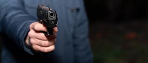 Bavaria, Germany - December 31, 2023: Man aims a pistol in the dark *** Mann zielt bei Dunkelheit mit einer Pistole