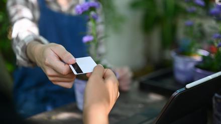 Blumenhändler nimmt Kreditkarte in Empfang. Mastercard und Visa haben sich innerhalb weniger Jahre bemerkenswert tief in den deutschen Markt für Debitkarten hineingefressen.